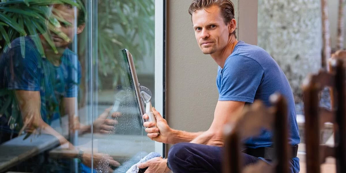 Man in blue shirt cleaning home replacement window. Man in blue shirt cleaning home replacement window.