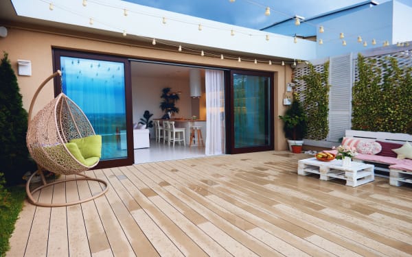 Los Angeles Patio Doors Modern outdoor patio with a hanging chair, string lights, and pallet sofa set near a glass-doored house.