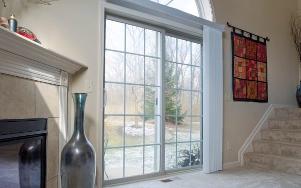 A living room with a fireplace and a large window, overlooking a snowy yard and trees.