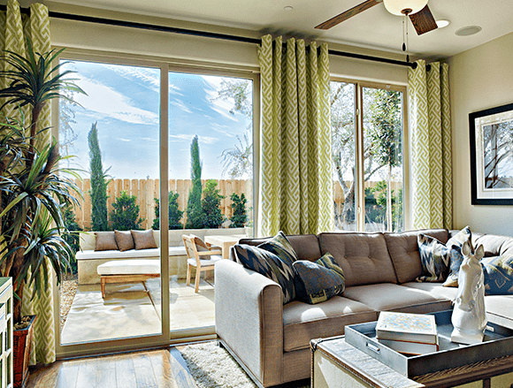 mv-photo-sliding-door modern door installation Modern open-plan living area with glass doors leading to a stylish patio with dining table, chairs, and greenery.